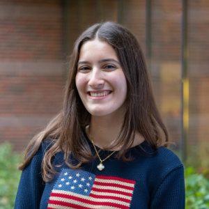 Saba Mehrzad, young Iranian American woman with long brown hair in a blue sweater with an American flag